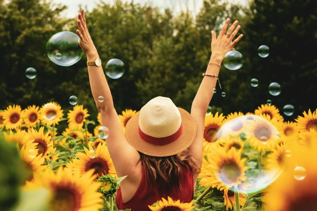 Woman sitting in flowers holding hands up